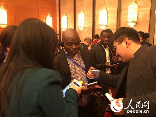 政协新闻发布会结束后，会上获得提问机会的尼日利亚记者Ikenna Emewu被中国记者围住。人民网记者贾玥 摄