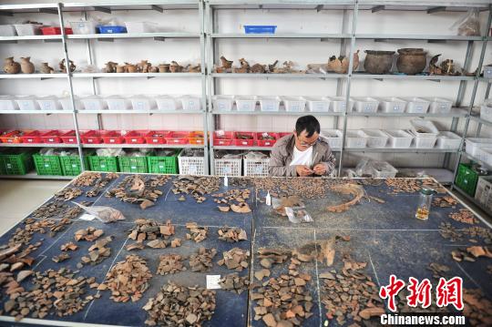 图为工作人员对出土的陶器碎片进行修复 刘冉阳 摄