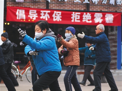  1月10日，山西省临汾市，市民一大早在鼓楼广场进行晨练，广场悬挂着“倡导环保 拒绝雾霾”的红色标语。