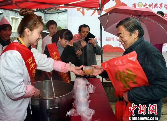 一名“90后”女青年志愿者为老年市民送上拗九粥和节日祝福。　记者刘可耕 摄