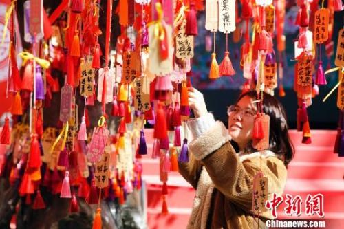 资料图：民众在上海大世界感受“海派年味”，游客在许愿树下祈福新年。　汤彦俊 摄