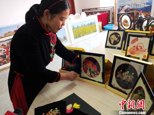 图为俞兰为记者展示她的麦秆画作品。　李隽 摄
