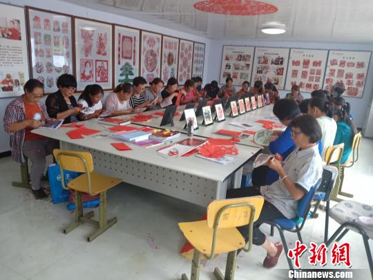 图为村民在非遗扶贫就业工坊练习剪纸 冯维健 摄