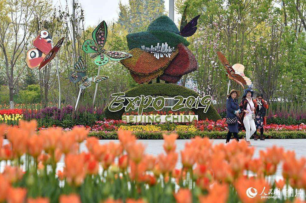4月29日，游客在世园会主题花坛前拍照留念。