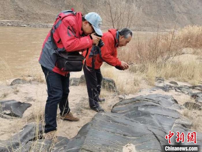 考古队正在拍摄新发现的人面像岩画。　周兴华 摄