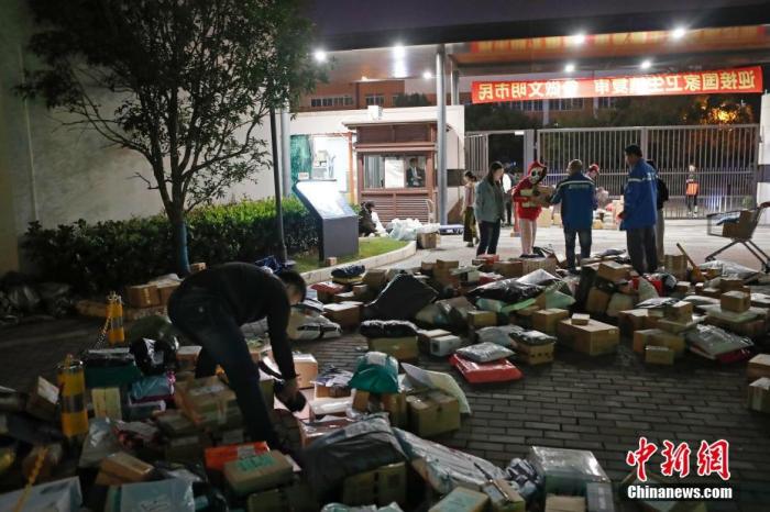 资料图：2019年11月15日晚，在上海虹桥乐贤居人才公寓，快递员在小区门前分拣快递物品。殷立勤 摄