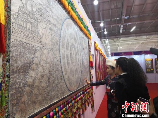 图为现场工作人员为参观者介绍世界上最大的银绘唐卡《香巴拉王国》。　杜萍 摄
