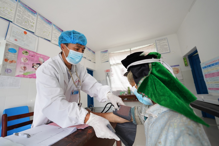 8月17日，在贵州省丹寨县排调镇甲石村卫生室，肖世军（左）给前来就诊的苗族村民检查病情。