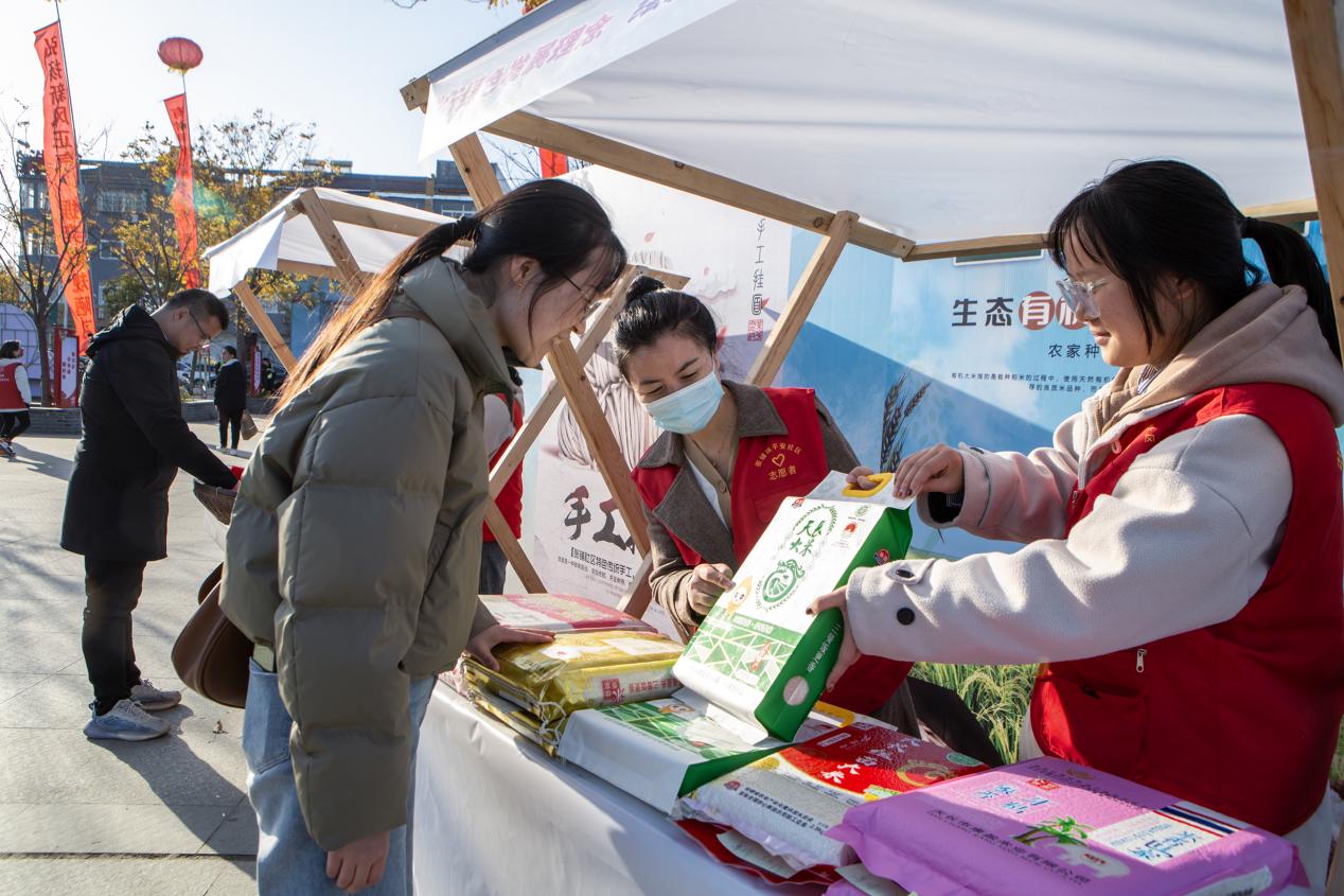 公益集市上，志愿者向群众推介特色农产品。毕玲摄